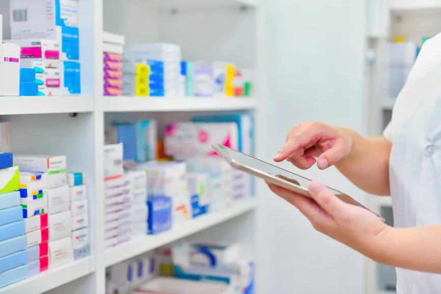 Pharmacy stocktaking image Pharmacist inventorying medication with tablet in pharmacy.